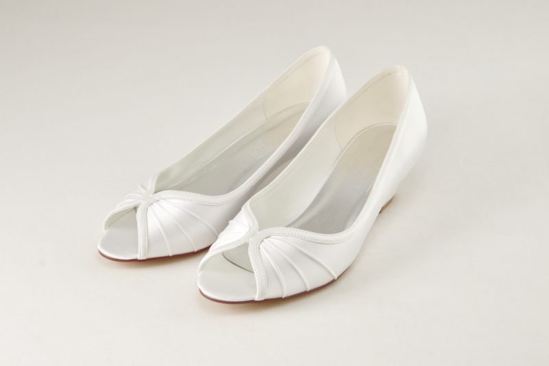 Bílé svatební boty na nízkém klínku s otevřenou špičkou. Na nártu odepínací kamínková spona.